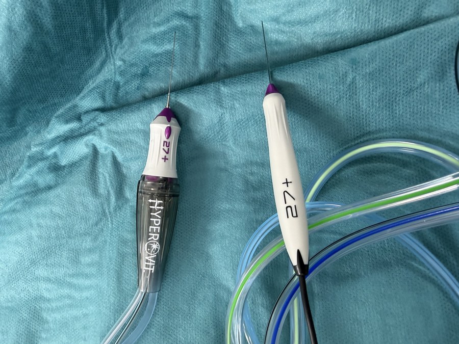 Two 27-gauge vitrectomy instruments laid on a surgical drape: the cutter with its aspiration tubing, and the light pipe, both with hair-thin shafts.